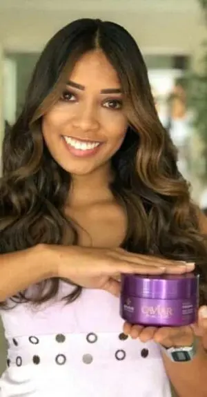 Modelo com cabelo perfeito e segurando o pote da Máscara de Nutrição Caviar Care da DYUSAR Cosméticos utilizado em sua hidratação